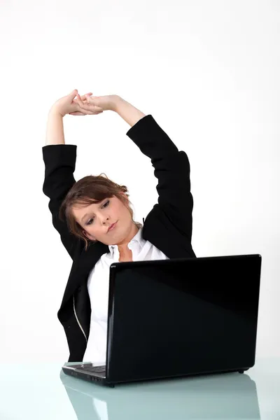 Donna d'affari seduto alla scrivania stretching — Foto Stock