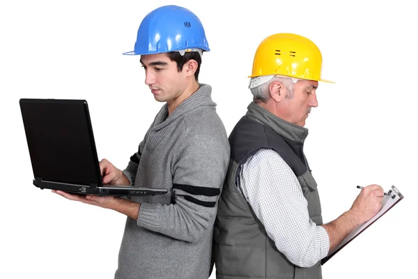 Builder and apprentice with laptop and clipboard — Stock Photo, Image