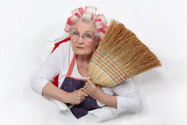 Granny with her hair in rollers holding a broom — Stock Photo, Image