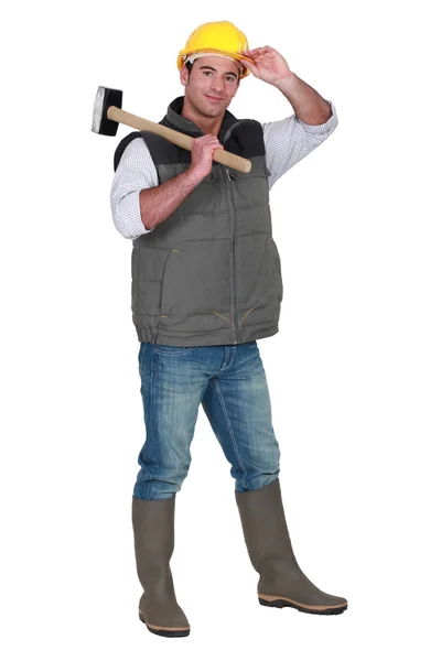 Tradesman carrying a mallet and wearing a hard hat and rubber boots — Stock Photo, Image