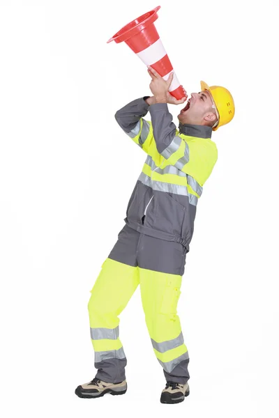 Un trabajador de la carretera usando un cono como un altavoz . —  Fotos de Stock