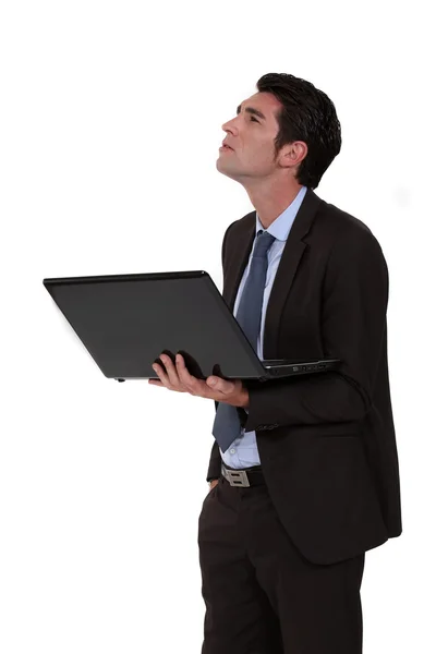 Empresário olhando para cima e segurando um laptop — Fotografia de Stock
