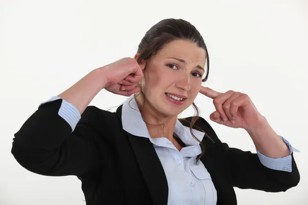 Zakenvrouw inpluggen haar oren. — Stockfoto