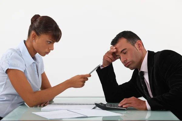 Stern woman with a man using a calculator — Stock Photo, Image