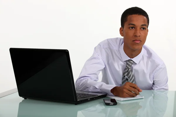 Joven hombre de negocios trabajando en su escritorio y pensando —  Fotos de Stock