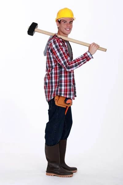 Jovem artesão segurando um enorme martelo em seu ombro — Fotografia de Stock