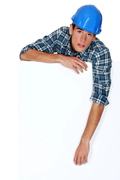 stock image Tradesman leaning against a blank sign