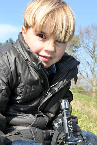 Jeune garçon avec un microscope à l'extérieur — Photo