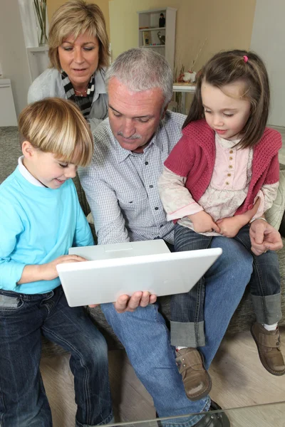 Ehepaar schaut mit Enkeln auf Laptop — Stockfoto
