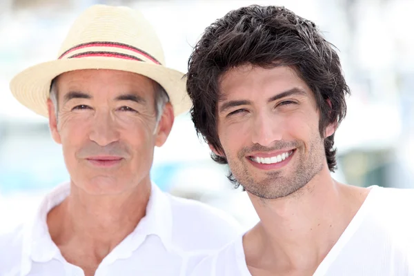 Hombre de 65 años con sombrero de paja y un hombre de 25 años posando en una suma —  Fotos de Stock