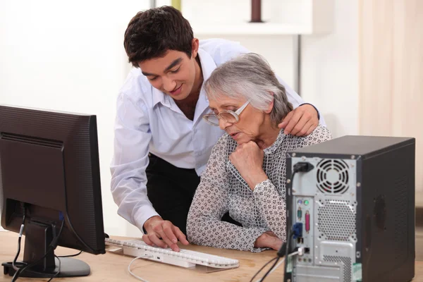 Giovane uomo mostrando computer nonna — Foto Stock