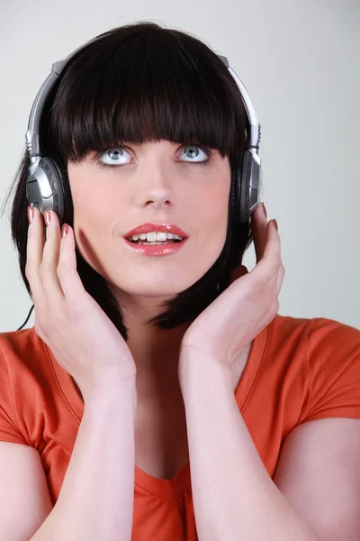 Vrouw luisteren naar muziek tegen studio achtergrond — Stockfoto
