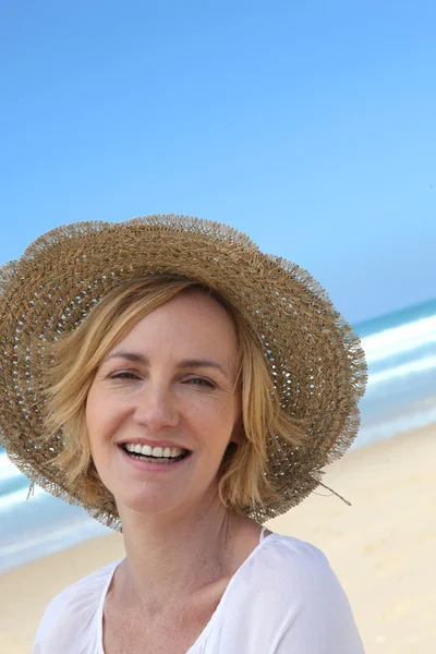 Sahilde hasır şapkalı gülümseyen kadın — Stok fotoğraf