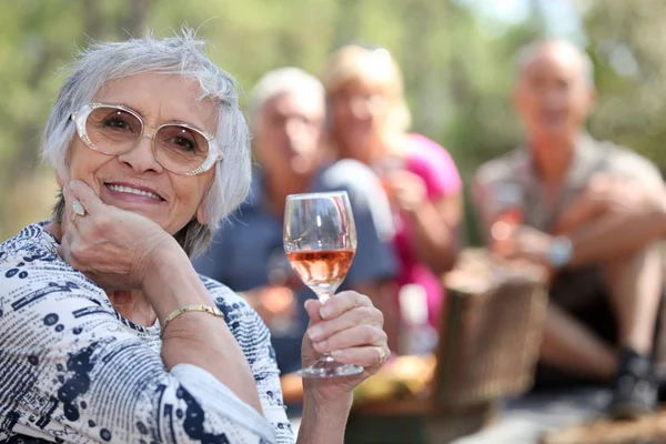 Starší žena sklenky růžové víno s přáteli na piknik — Stock fotografie