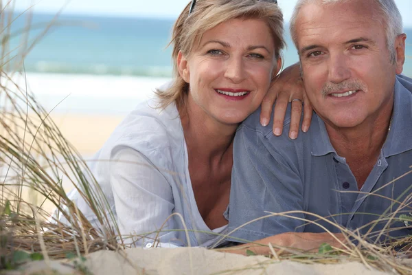 Feküdt a homokdűnék középső idős pár — Stock Fotó