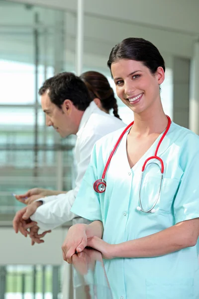 Улыбающаяся медсестра, стоящая с коллегами — стоковое фото