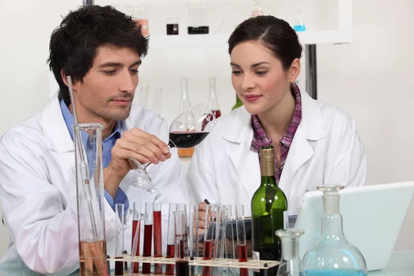 Mężczyzna i kobieta testowanie wina w laboratorium — Zdjęcie stockowe