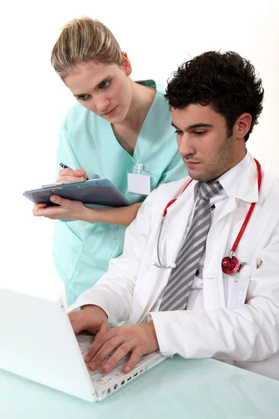 Una enfermera y un médico revisando su portátil . — Foto de Stock