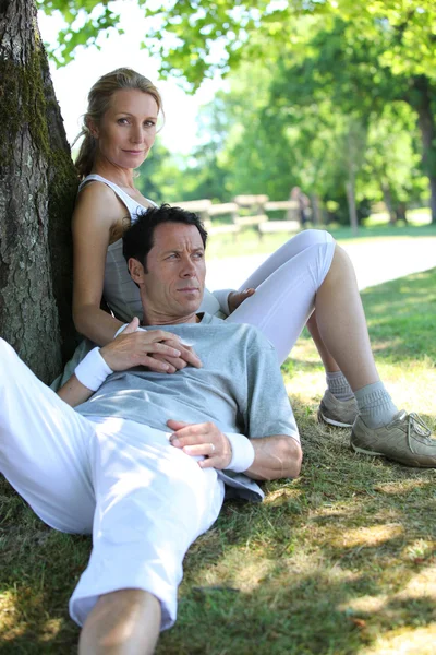 Retrato de casal desportivo relaxante por árvore — Fotografia de Stock