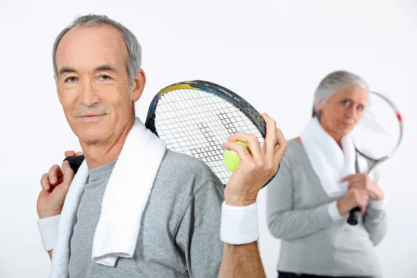 Pareja mayor con raquetas de tenis — Foto de Stock