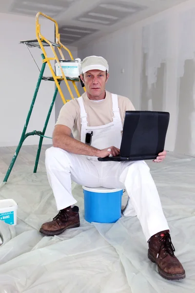 Maler macht Pause, um seinen Laptop zu benutzen — Stockfoto