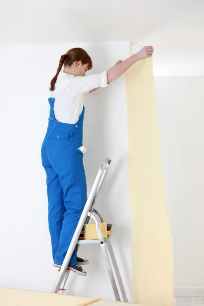 stock image Woman on ladder laying wallpaper