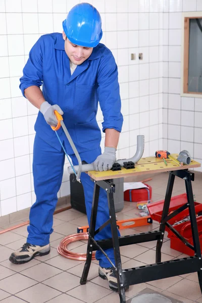 Plumber sawing grey plastic pipe — Stock Photo, Image