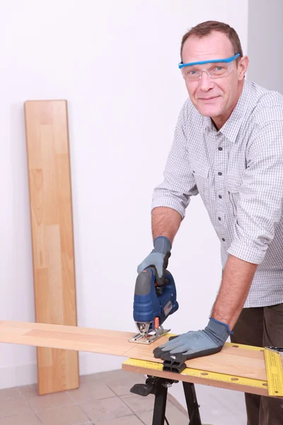 Sorrindo homem serrar piso laminado — Fotografia de Stock