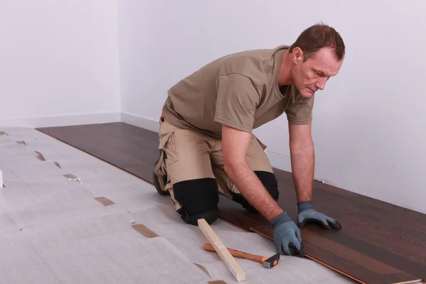 Homem que estabelece piso laminado — Fotografia de Stock