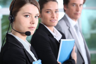 Three employees stood together holding documents clipart