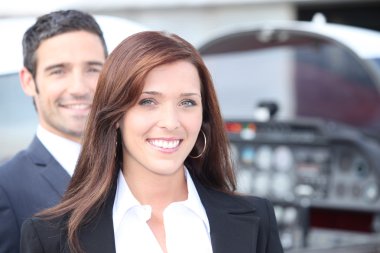 Couple standing by the cockpit of a light aircraft clipart