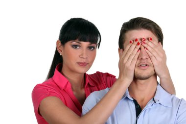 Woman putting her hands on man eyes clipart