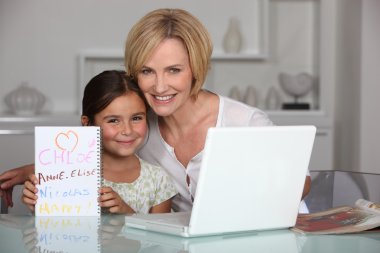 Mother and daughter in dining room with laptop clipart