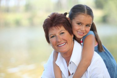 Young girl riding piggy-back on her grandmother's back clipart