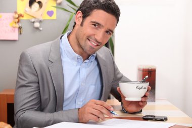 Businessman working in his kitchen with a cup of coffee clipart