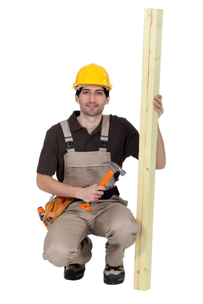 Carpenter with plank of wood and hammer — Stock Photo, Image