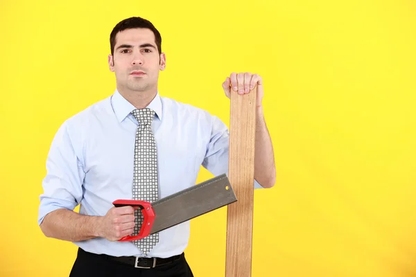 Profesional sosteniendo una sierra y un tablón de madera — Foto de Stock