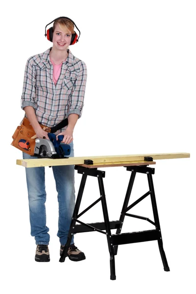 Woman using a circular saw to cut a wooden plank — Stock Photo, Image