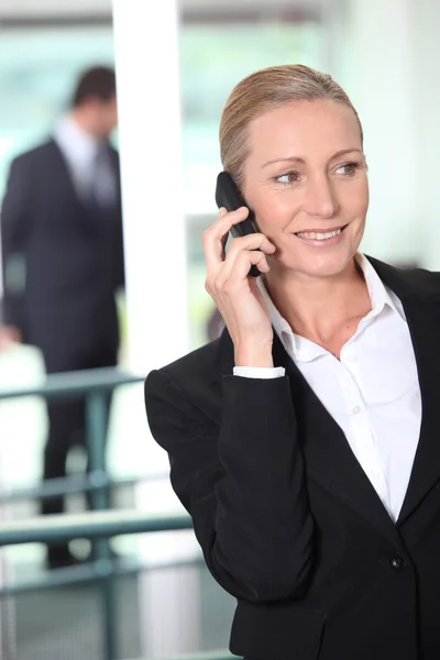 Donna d'affari intelligente che utilizza un telefono cellulare in un ambiente di ufficio — Foto Stock