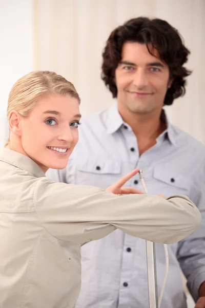 Woman pointing the end of a cable out to a man — Stock Photo, Image