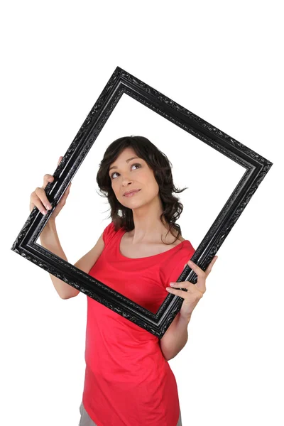 Young woman carrying black frame, studio shot — Stock Photo, Image