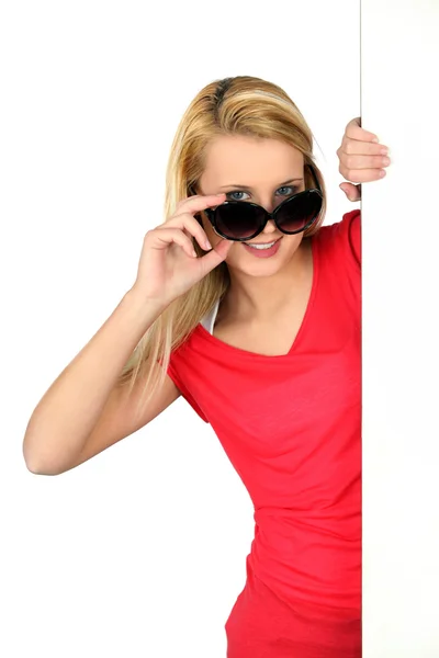 Donna che sbircia sopra occhiali da sole di grandi dimensioni — Foto Stock