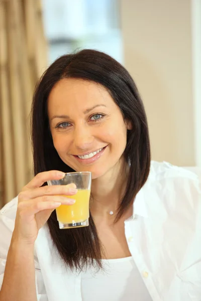 Тридцатилетняя брюнетка пьет апельсиновый сок — стоковое фото