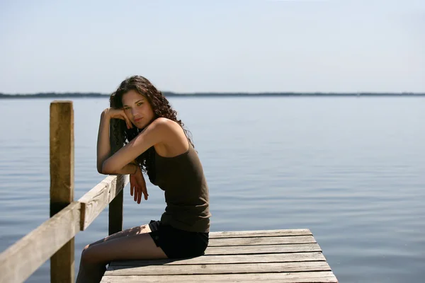 Jolie brune assise seule sur une jetée — Photo