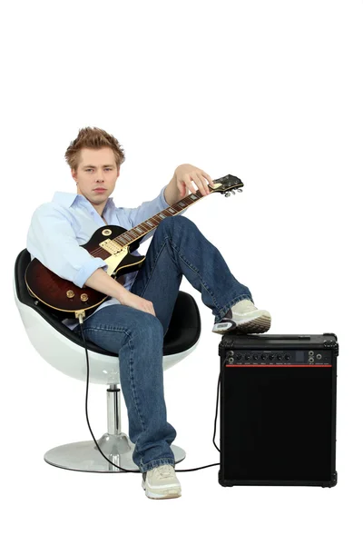 Мальчик в кресле с гитарой и усилителем — стоковое фото
