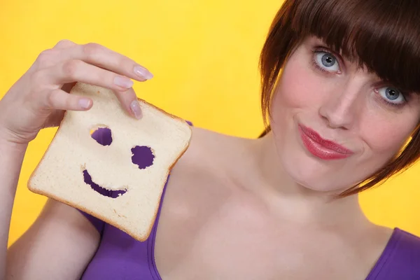 Vrouw met een smiley stukje brood — Stockfoto