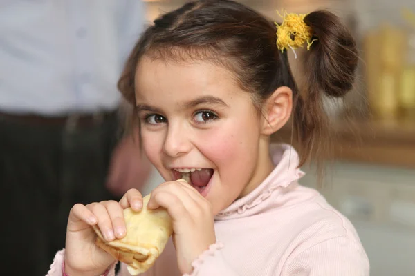 Menina feliz comer uma panqueca — Fotografia de Stock