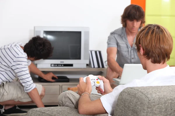 Tre kompisar spelar TV-spel. — Stockfoto