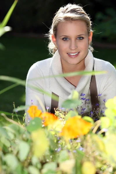 꽃 뒤에 서 있는 젊은 여자 — 스톡 사진