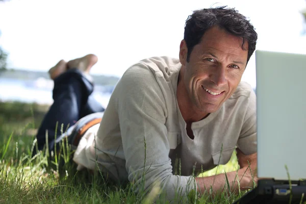 Muž s úsměvem práce na trávě — Stock fotografie
